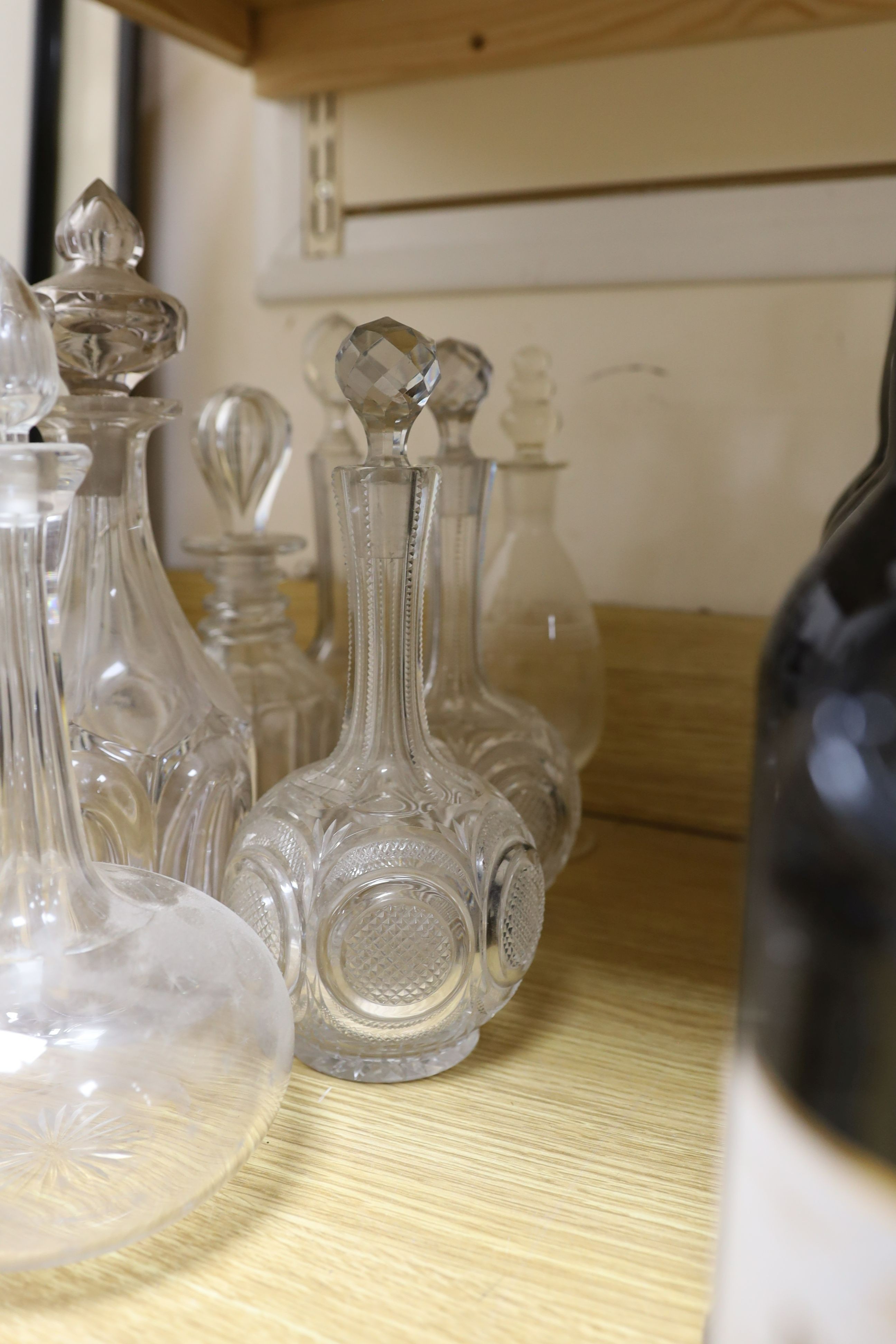 Sundry glassware including a six bottle cruet set on a plated stand, a Victorian cut glass jug, a pair of long neck decanters, five other decanters and a glass cake tazza